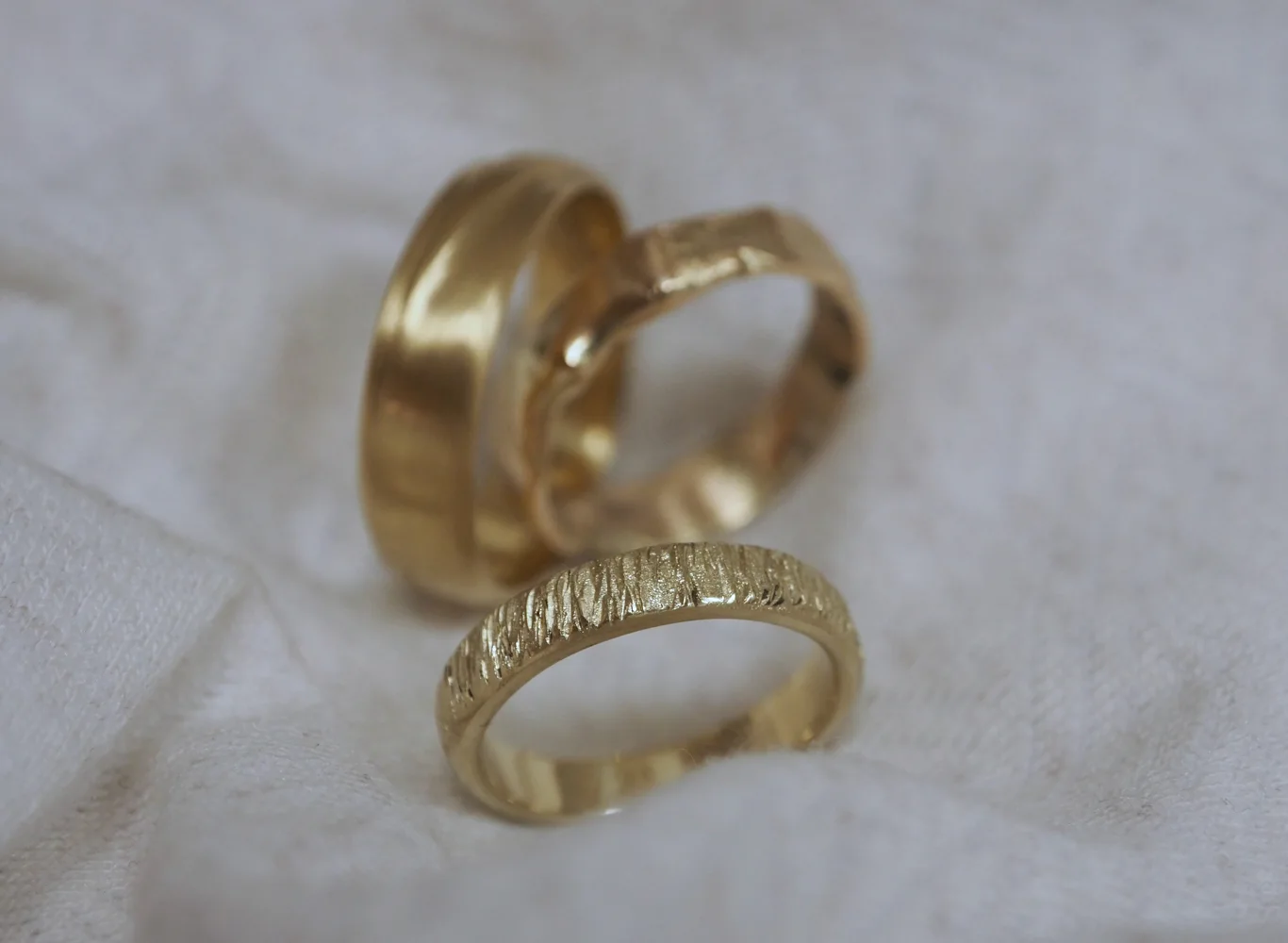 Drei Trauringe mit unterschiedlichen Strukturen aus Gelbgold von Solitaire Lechler Freiburg